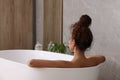 African American woman taking bath indoors, back view. Space for text Royalty Free Stock Photo