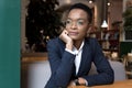 An African-American woman is thinking while sitting in a cafe, a serious business woman is looking out the window Royalty Free Stock Photo