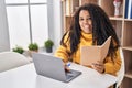 African american woman using laptop reading book at home Royalty Free Stock Photo