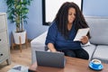 African american woman using laptop reading notebook at home Royalty Free Stock Photo