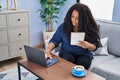 African american woman using laptop reading notebook at home Royalty Free Stock Photo