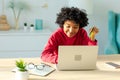 African american woman using laptop shopping online paying with gold credit card. Girl sitting at home buying on Royalty Free Stock Photo