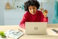 African american woman using laptop shopping online paying with gold credit card. Girl sitting at home buying on Royalty Free Stock Photo