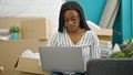 African american woman using laptop sitting on sofa at new home Royalty Free Stock Photo