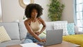 African american woman using laptop sitting on sofa suffering stomachache at home Royalty Free Stock Photo