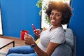 African american woman using smartphone drinking coffee at home Royalty Free Stock Photo