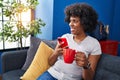 African american woman using smartphone drinking coffee at home Royalty Free Stock Photo