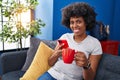 African american woman using smartphone drinking coffee at home Royalty Free Stock Photo