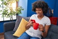 African american woman using smartphone drinking coffee at home Royalty Free Stock Photo