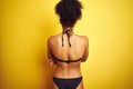 African american woman on vacation wearing bikini standing over isolated yellow background standing backwards looking away with Royalty Free Stock Photo