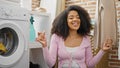 African american woman waiting for washing machine sitting on floor dancing at laundry room Royalty Free Stock Photo