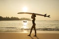 African american woman walking with surfboard on her head on ocean beach. Black female surfer posing with surf board Royalty Free Stock Photo