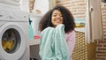 African american woman washing clothes smelling clean towel at laundry room Royalty Free Stock Photo