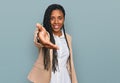 African american woman wearing business jacket smiling friendly offering handshake as greeting and welcoming