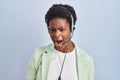 African american woman wearing call center agent headset angry and mad screaming frustrated and furious, shouting with anger