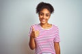 African american woman wearing casual pink striped t-shirt over isolated white background doing happy thumbs up gesture with hand Royalty Free Stock Photo