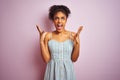 African american woman wearing casual striped dress standing over isolated pink background crazy and mad shouting and yelling with Royalty Free Stock Photo