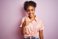 African american woman wearing casual striped shirt standing over isolated pink background doing happy thumbs up gesture with hand Royalty Free Stock Photo