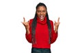 African american woman wearing casual winter sweater shouting with crazy expression doing rock symbol with hands up Royalty Free Stock Photo