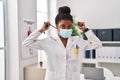 African american woman wearing doctor uniform and medical mask holding stethoscope at clinic Royalty Free Stock Photo