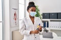 African american woman wearing doctor uniform and medical mask holding stethoscope at clinic Royalty Free Stock Photo
