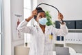 African american woman wearing doctor uniform and medical mask holding stethoscope at clinic Royalty Free Stock Photo