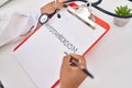 African american woman wearing doctor uniform writing hypothyroidism word on clipboard at clinic