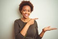 African american woman wearing earphones listening to music over isolated background amazed and smiling to the camera while Royalty Free Stock Photo