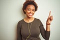 African american woman wearing earphones listening to music over isolated background with a big smile on face, pointing with hand Royalty Free Stock Photo