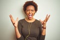 African american woman wearing earphones listening to music over isolated background celebrating crazy and amazed for success with Royalty Free Stock Photo