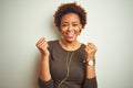 African american woman wearing earphones listening to music over isolated background celebrating surprised and amazed for success Royalty Free Stock Photo