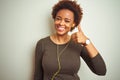 African american woman wearing earphones listening to music over isolated background doing happy thumbs up gesture with hand Royalty Free Stock Photo