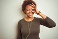 African american woman wearing earphones listening to music over isolated background doing ok gesture with hand smiling, eye Royalty Free Stock Photo