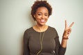 African american woman wearing earphones listening to music over isolated background smiling with happy face winking at the camera Royalty Free Stock Photo