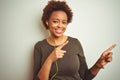 African american woman wearing earphones listening to music over isolated background smiling and looking at the camera pointing Royalty Free Stock Photo