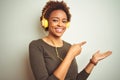 African american woman wearing headphones listening to music over isolated background amazed and smiling to the camera while Royalty Free Stock Photo