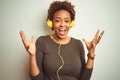 African american woman wearing headphones listening to music over isolated background celebrating crazy and amazed for success Royalty Free Stock Photo