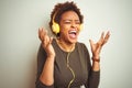 African american woman wearing headphones listening to music over isolated background celebrating mad and crazy for success with Royalty Free Stock Photo