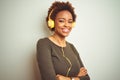 African american woman wearing headphones listening to music over isolated background happy face smiling with crossed arms looking Royalty Free Stock Photo