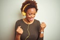 African american woman wearing headphones listening to music over isolated background very happy and excited doing winner gesture Royalty Free Stock Photo