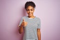 African american woman wearing navy striped t-shirt standing over isolated pink background doing happy thumbs up gesture with hand Royalty Free Stock Photo