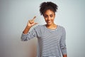 African american woman wearing navy striped t-shirt standing over isolated white background smiling and confident gesturing with Royalty Free Stock Photo