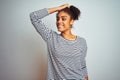 African american woman wearing navy striped t-shirt standing over isolated white background smiling confident touching hair with Royalty Free Stock Photo