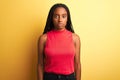 African american woman wearing red casual t-shirt standing over isolated yellow background Relaxed with serious expression on face Royalty Free Stock Photo