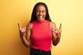 African american woman wearing red casual t-shirt standing over isolated yellow background shouting with crazy expression doing Royalty Free Stock Photo
