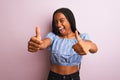 African american woman wearing striped t-shirt standing over isolated pink background approving doing positive gesture with hand, Royalty Free Stock Photo