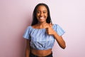 African american woman wearing striped t-shirt standing over isolated pink background doing happy thumbs up gesture with hand Royalty Free Stock Photo