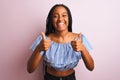 African american woman wearing striped t-shirt standing over isolated pink background success sign doing positive gesture with Royalty Free Stock Photo