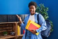 African american woman wearing student backpack and holding books celebrating victory with happy smile and winner expression with Royalty Free Stock Photo