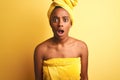 African american woman wearing towel after shower standing over  yellow background afraid and shocked with surprise Royalty Free Stock Photo